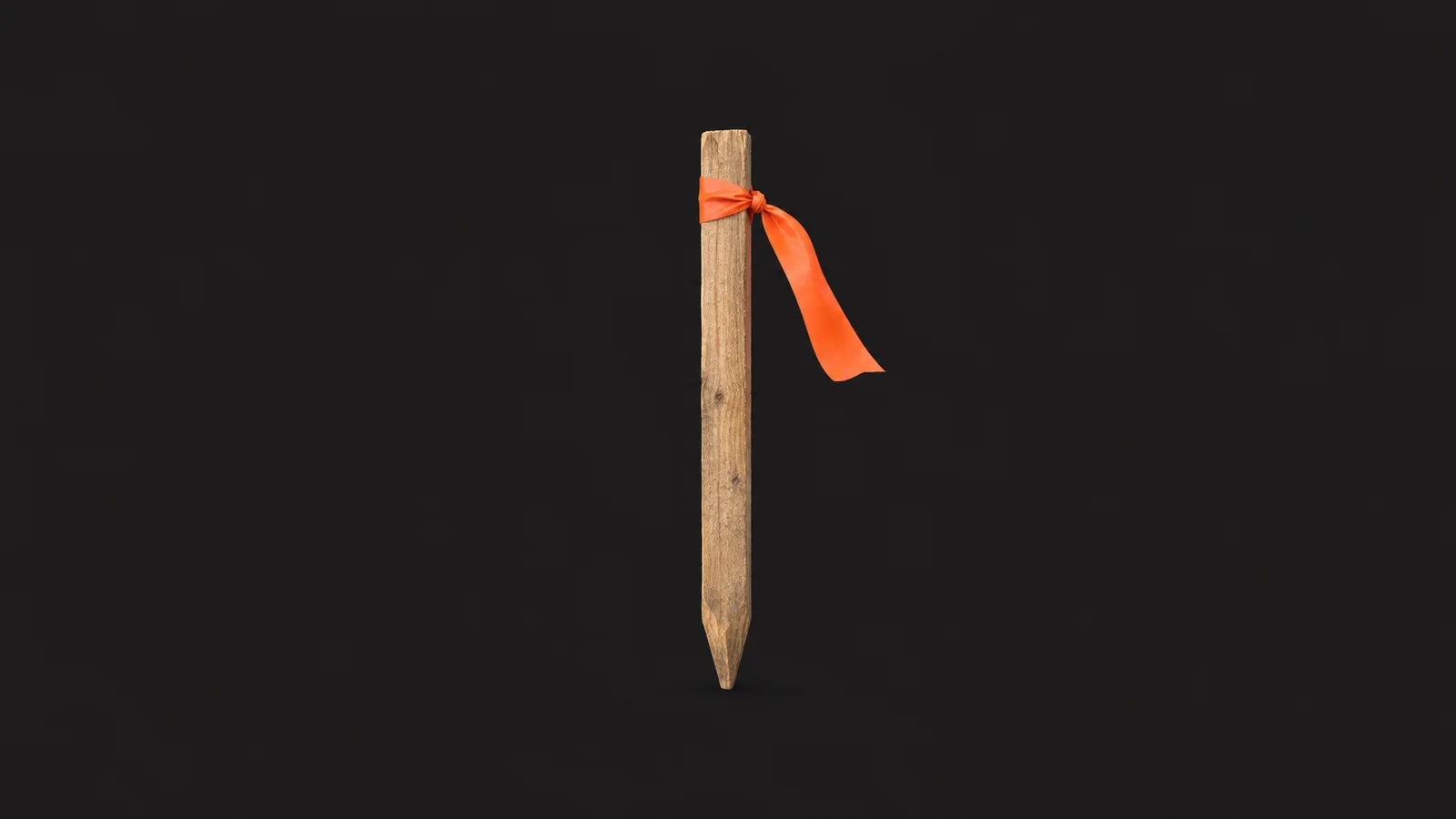 Isolated a wooden survey peg with a ribbon of orange flagging tape centred on a seamless deep charcoal near-black studio background, generous empty margin on every side for overlaid branding