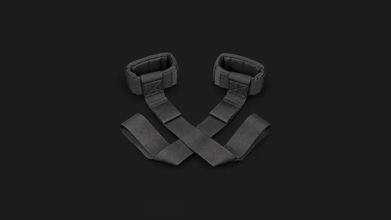 Isolated a piano-mover's forearm lifting straps laid out flat centred on a seamless deep charcoal near-black studio background, generous empty margin on every side for overlaid branding
