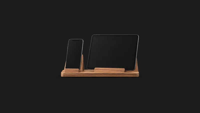 Isolated a wooden phone and tablet display stand with no screen content centred on a seamless deep charcoal near-black studio background, generous empty margin on every side for overlaid branding