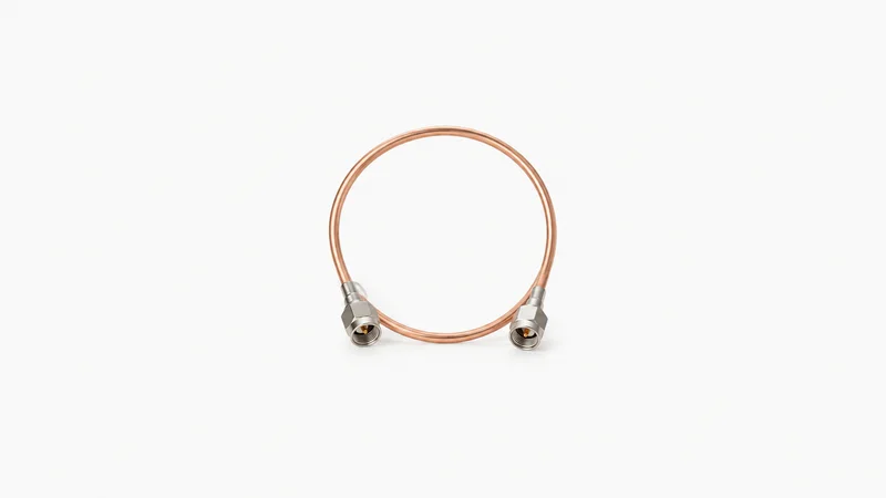 Isolated a coaxial semi-rigid cable bent into a loop centred on a seamless pale off-white studio background, generous empty margin on every side for overlaid branding