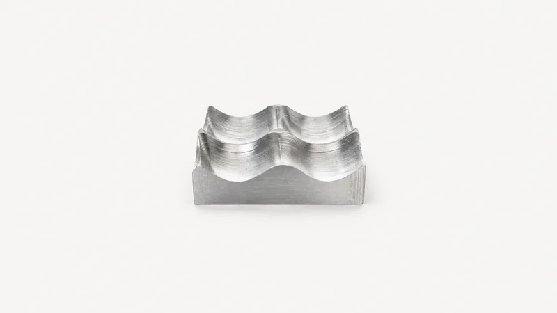 Abstract a scalloped surface of overlapping ball-mill tool paths in brushed aluminium motif centred on a seamless pale off-white studio background, generous empty margin for overlaid branding