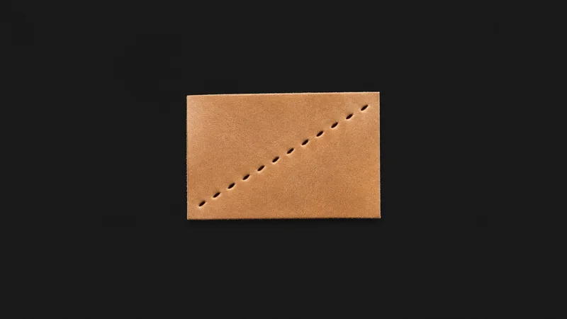 Abstract a diagonal row of saddle-stitch holes running across a tan leather plane motif centred on a seamless deep charcoal near-black studio background, generous empty margin for overlaid branding