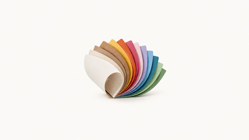Abstract a fan of paper sheets curling in a graduated spectrum motif centred on a seamless pale off-white studio background, generous empty margin for overlaid branding