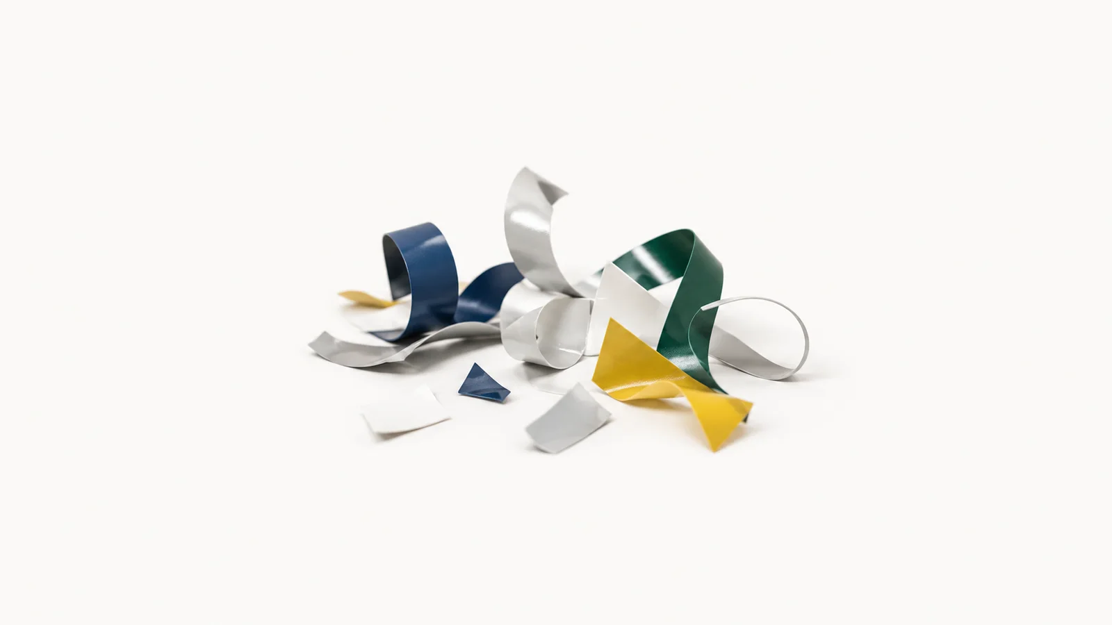 Abstract a scatter of weeded vinyl offcuts curling upward motif centred on a seamless pale off-white studio background, generous empty margin for overlaid branding