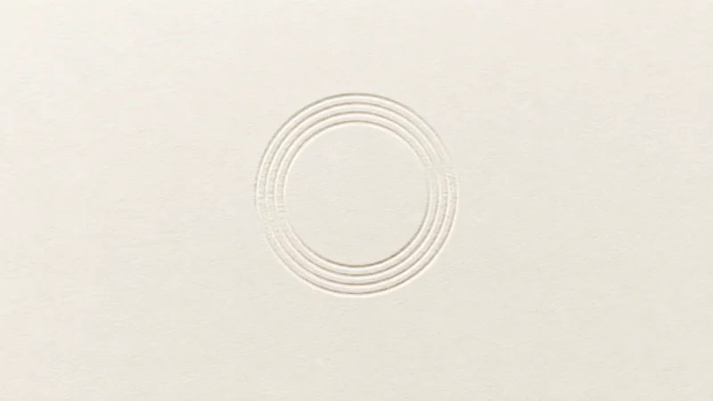 Abstract a ring of concentric ridges pressed into cream card stock motif centred on a seamless pale off-white studio background, generous empty margin for overlaid branding