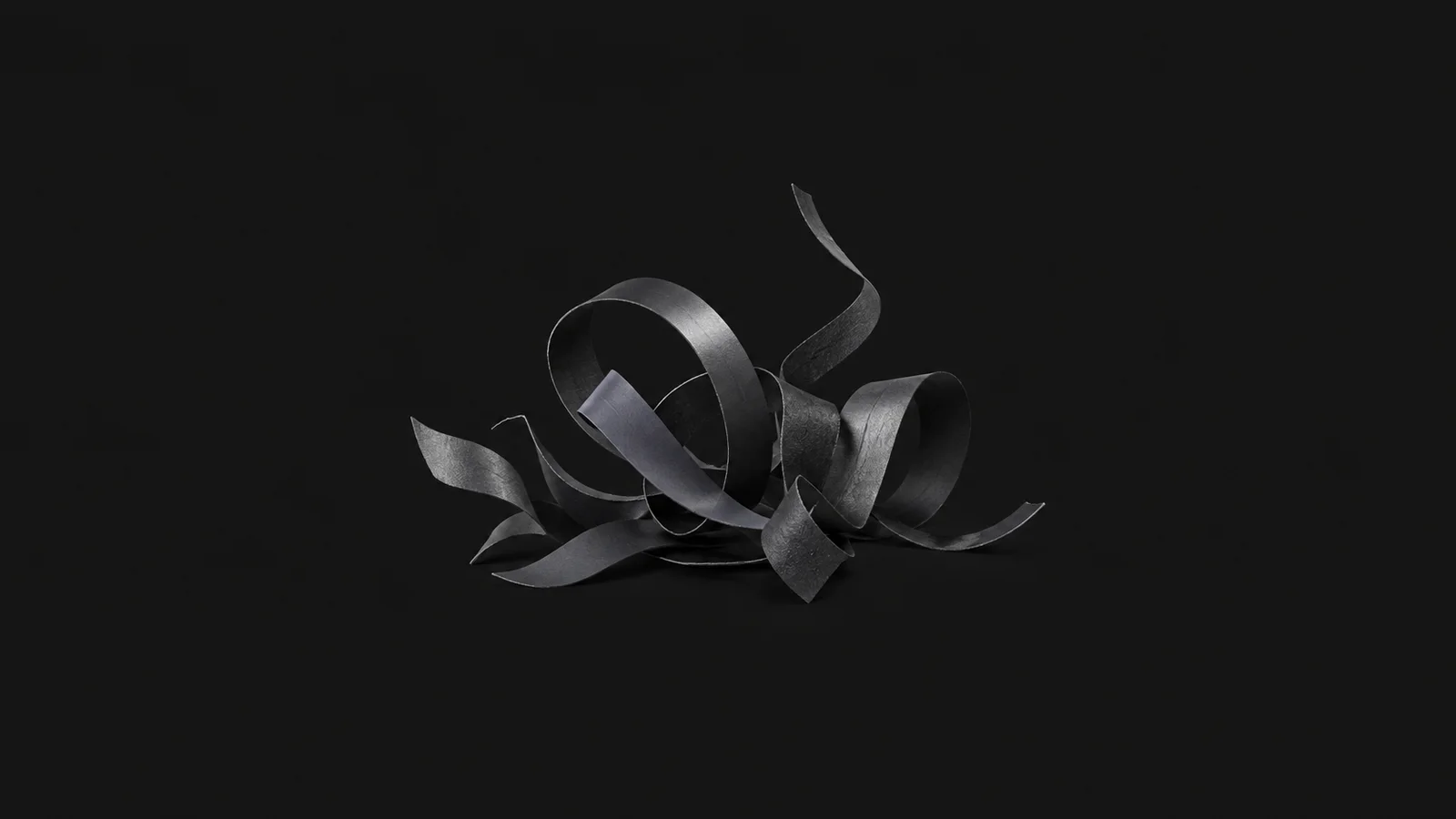 Abstract a scatter of weeded vinyl offcuts curling upward motif centred on a seamless deep charcoal near-black studio background, generous empty margin for overlaid branding