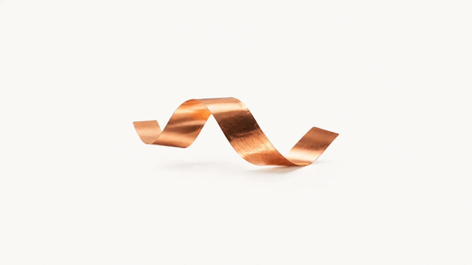 Abstract a flowing ribbon of copper foil catching amber light motif centred on a seamless pale off-white studio background, generous empty margin for overlaid branding