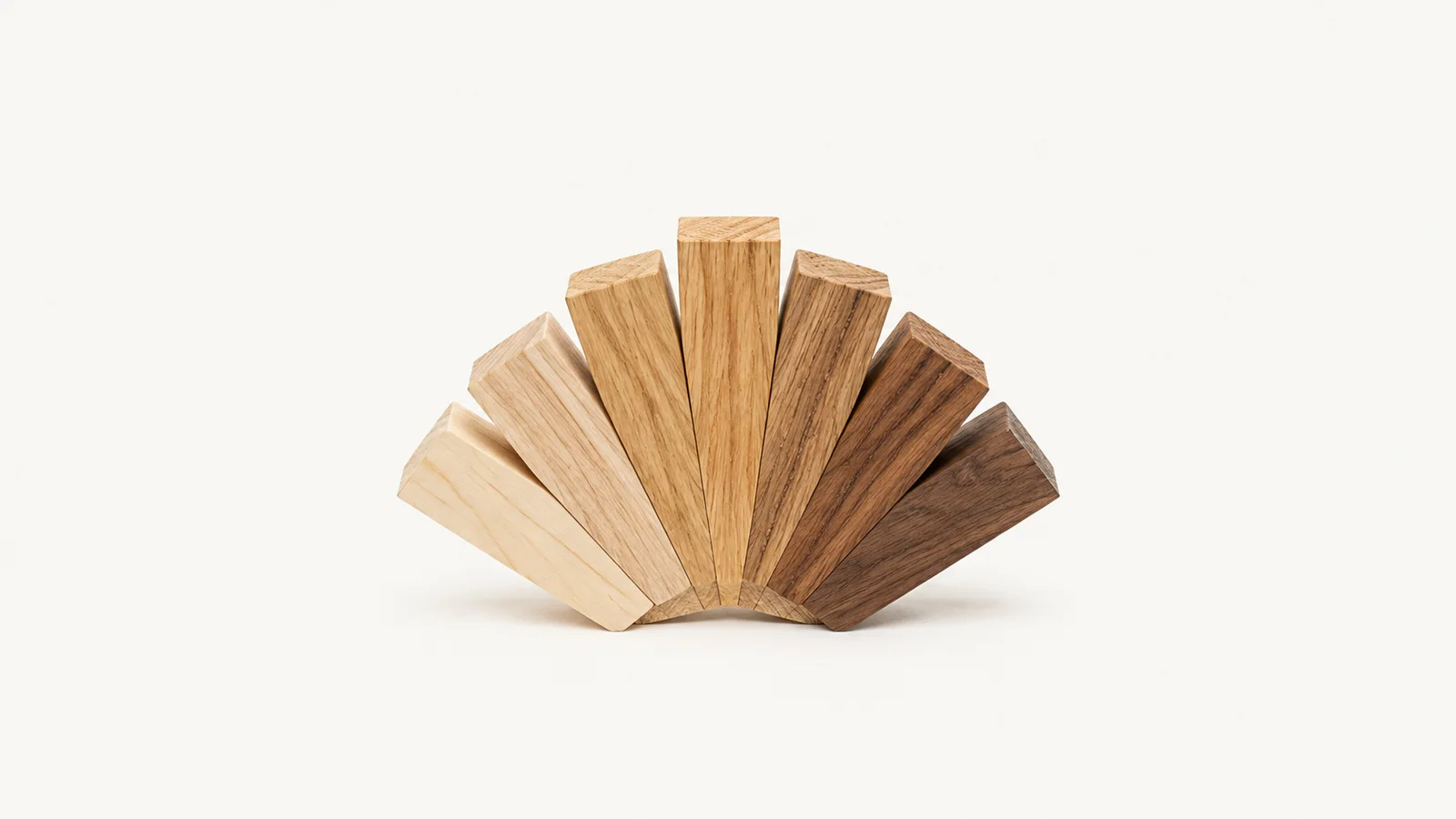 Abstract a fan of timber offcuts in graduated grain tones motif centred on a seamless pale off-white studio background, generous empty margin for overlaid branding