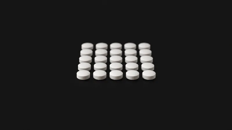 Abstract a grid of white tablets receding into soft focus motif centred on a seamless deep charcoal near-black studio background, generous empty margin for overlaid branding