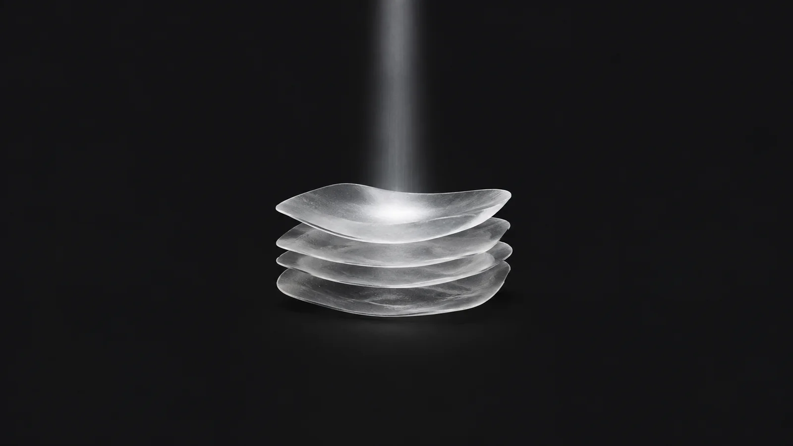 Abstract a soft cushion of stacked frosted layers absorbing a falling light beam motif centred on a seamless deep charcoal near-black studio background, generous empty margin for overlaid branding