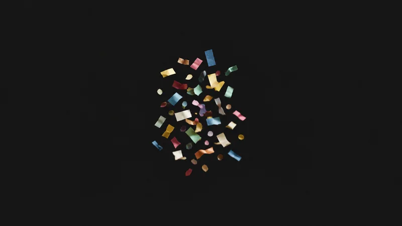 Abstract a burst of coloured paper confetti frozen mid-fall motif centred on a seamless deep charcoal near-black studio background, generous empty margin for overlaid branding