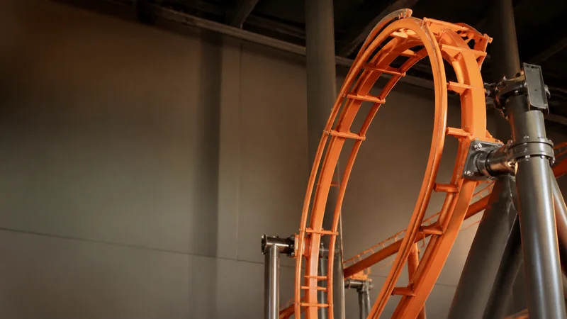 Close, clean detail of the looping roller coaster track, warm interior light, no people in frame
