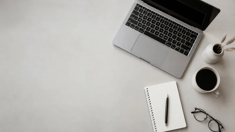 Styled flat-lay of laptop, notebook and coffee on a clean background, clean even studio light, generous negative space for overlaid text