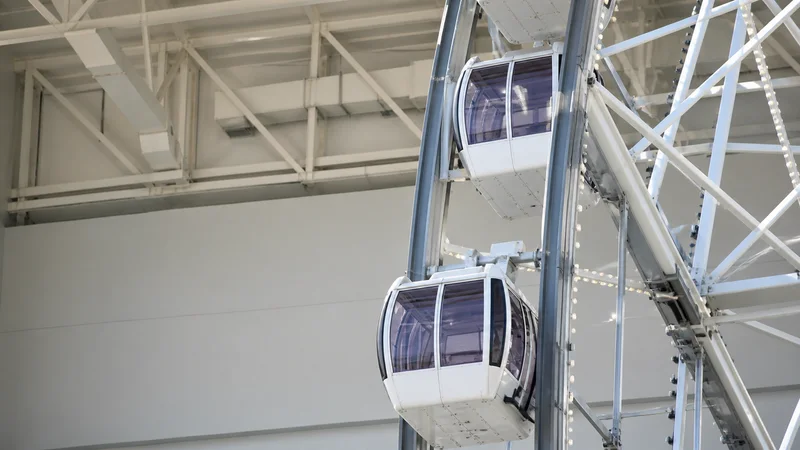 Close, clean detail of the ferris wheel with gondolas, soft even indoor light, no people in frame