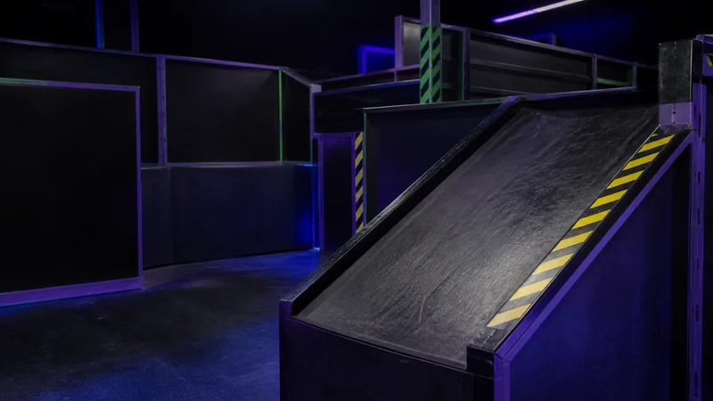 Close, clean detail of the blacklit maze ramps and barriers, soft even indoor light, no people in frame