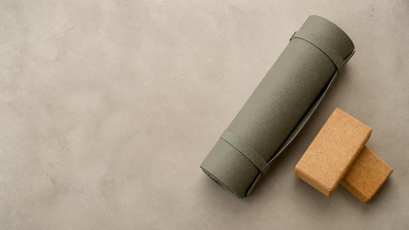 Styled flat-lay of a rolled yoga mat and cork blocks on a clean background, clean even studio light, generous negative space for overlaid text
