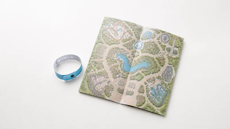 Styled flat-lay of ride wristband and park map on a clean background, clean even studio light, generous negative space for overlaid text