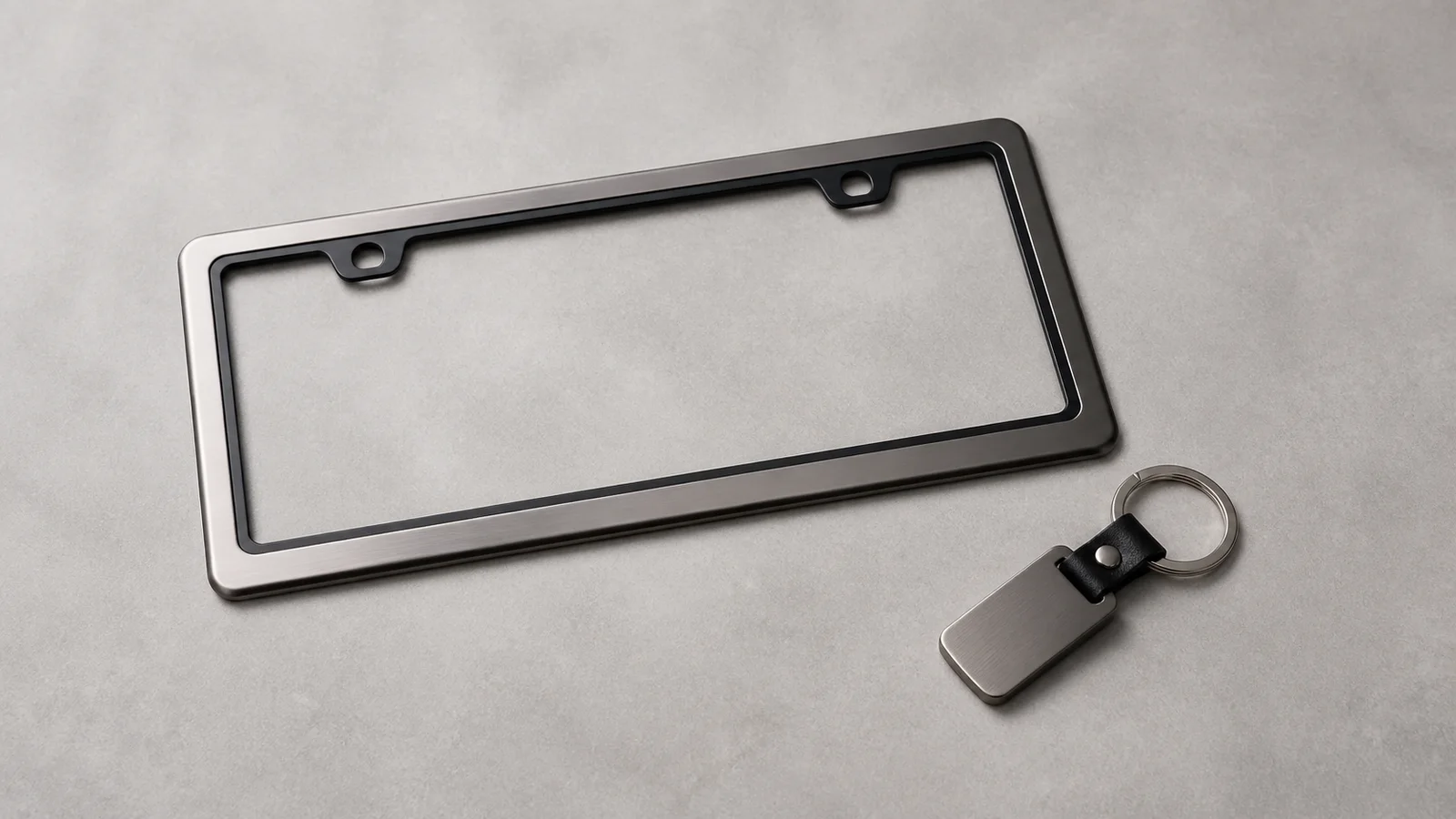 Styled flat-lay of dealership license-plate frame and keychain on a clean background, soft studio light, generous negative space for overlaid text