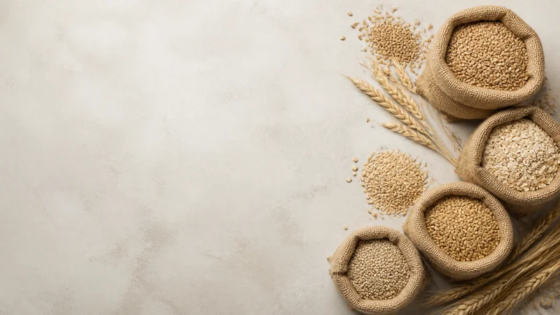 Styled flat-lay of sacks of harvested grain on a clean background, soft studio light, generous negative space for overlaid text