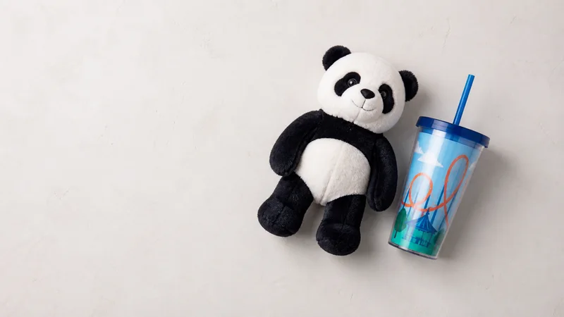 Styled flat-lay of plush prize and souvenir cup on a clean background, clean even studio light, generous negative space for overlaid text