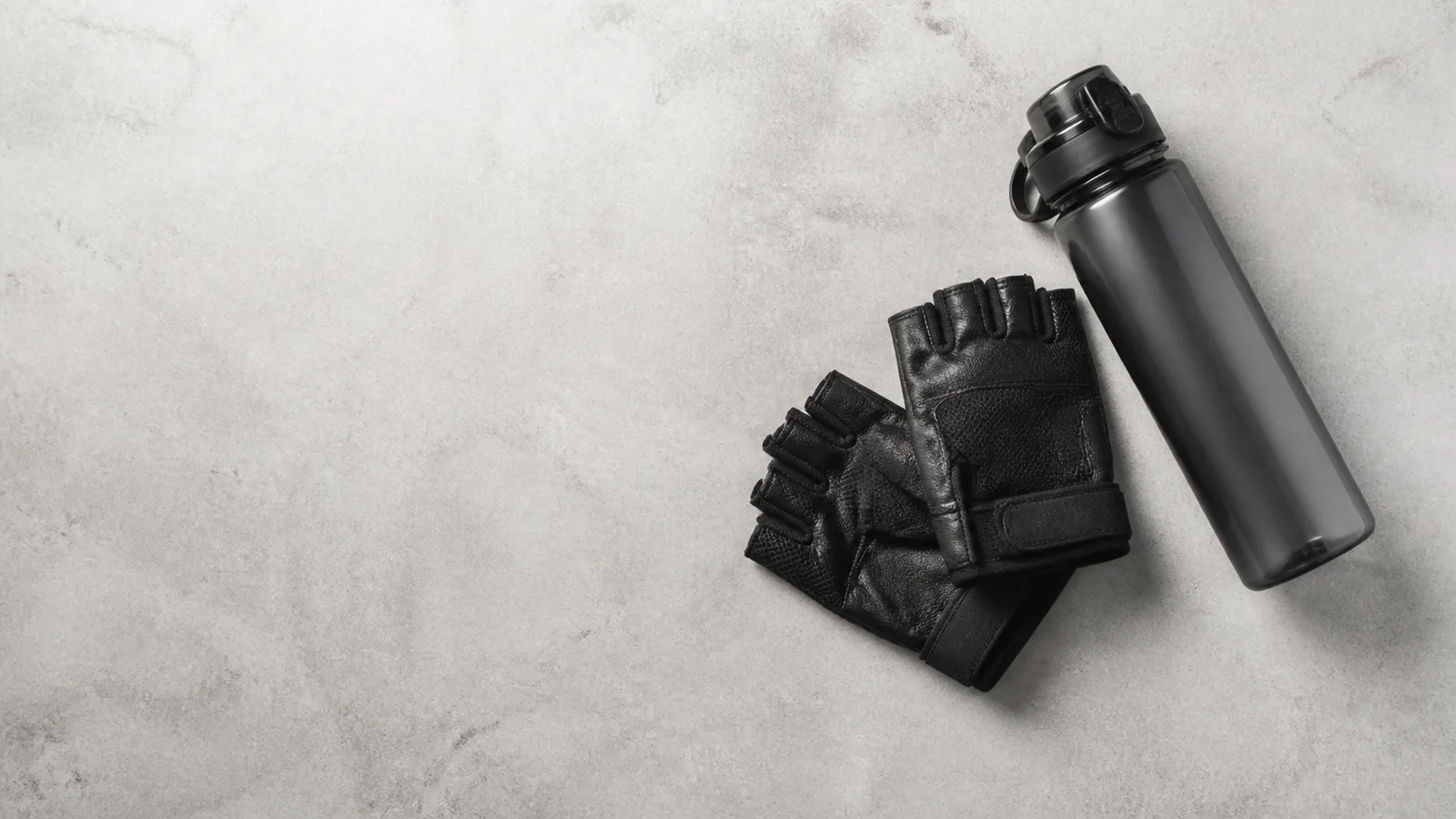 Styled flat-lay of water bottle and gym gloves on a clean background, clean even studio light, generous negative space for overlaid text