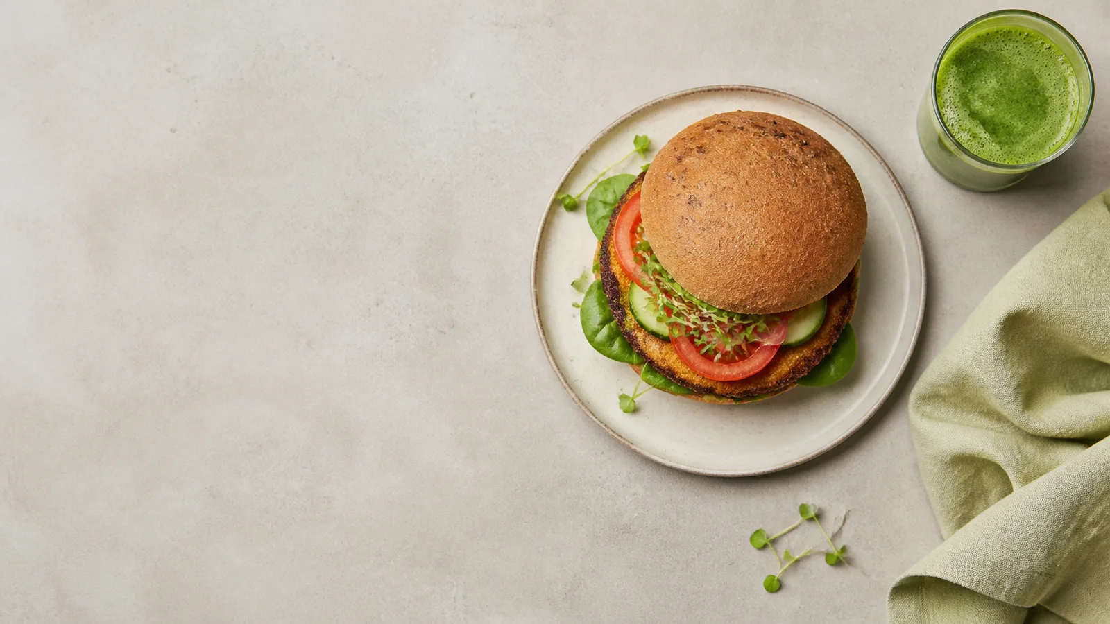 Styled flat-lay of a plant-based burger and juice on a clean background, clean even studio light, generous negative space for overlaid text