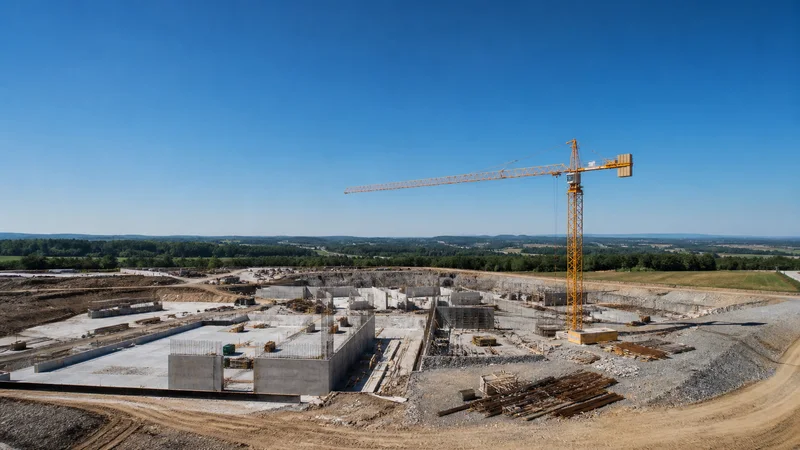 High aerial of a active construction site with a tower crane, a clear blue sky, uncluttered ground and sky bands