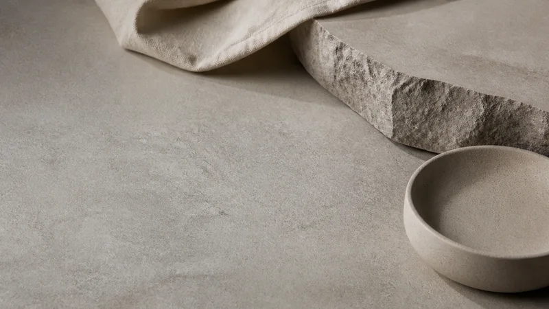 Minimal textured neutral surface, soft studio light, wide clean copy space to one side