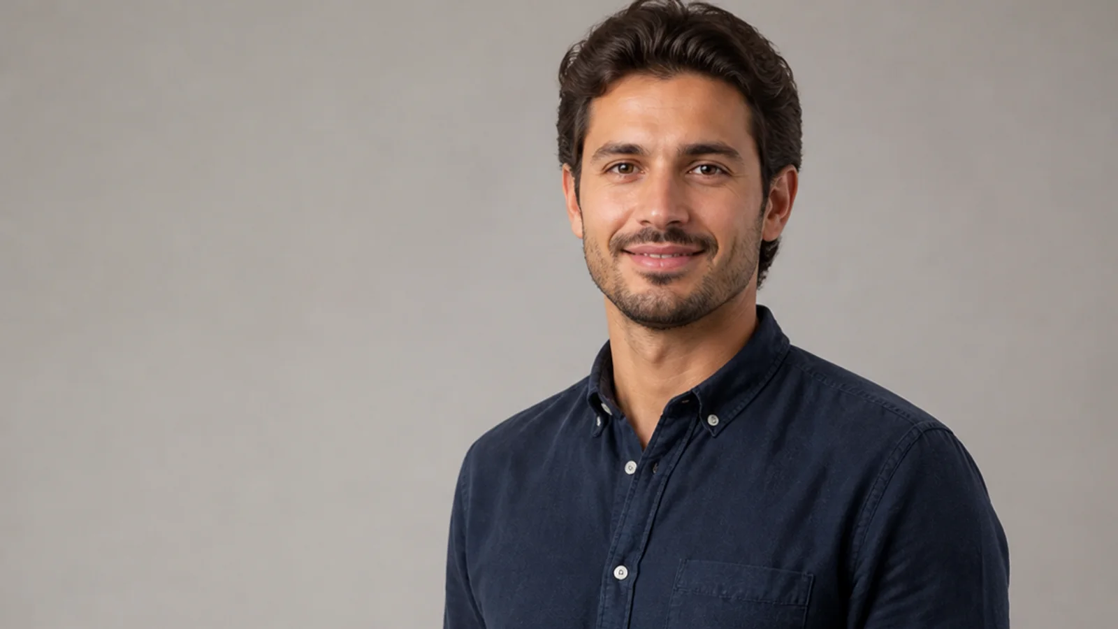 Mid-length portrait of a young adult in casual wear, plain backdrop with copy space, soft studio light