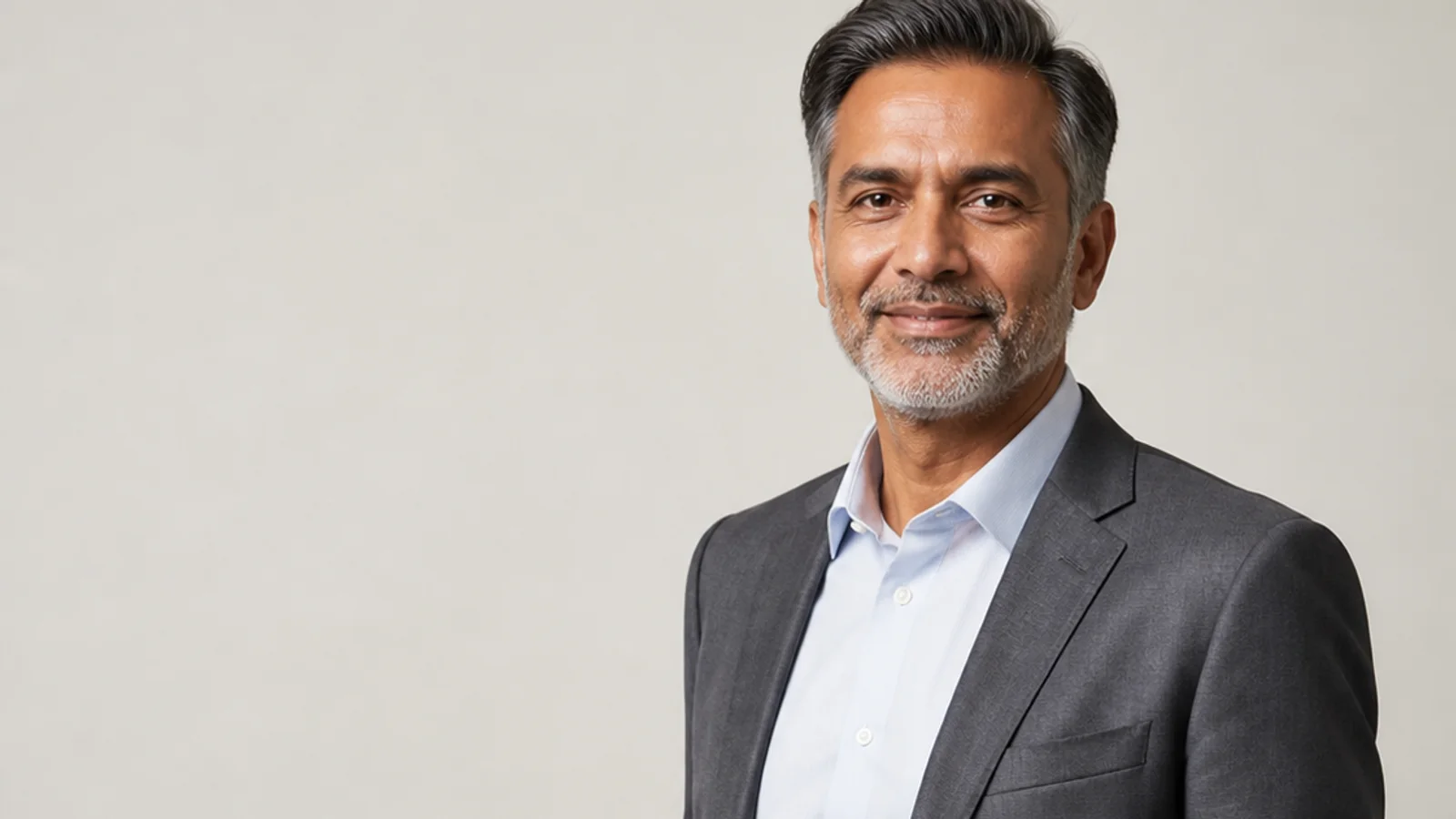 Mid-length portrait of a middle-aged professional in business attire, plain backdrop with copy space, clean even studio light