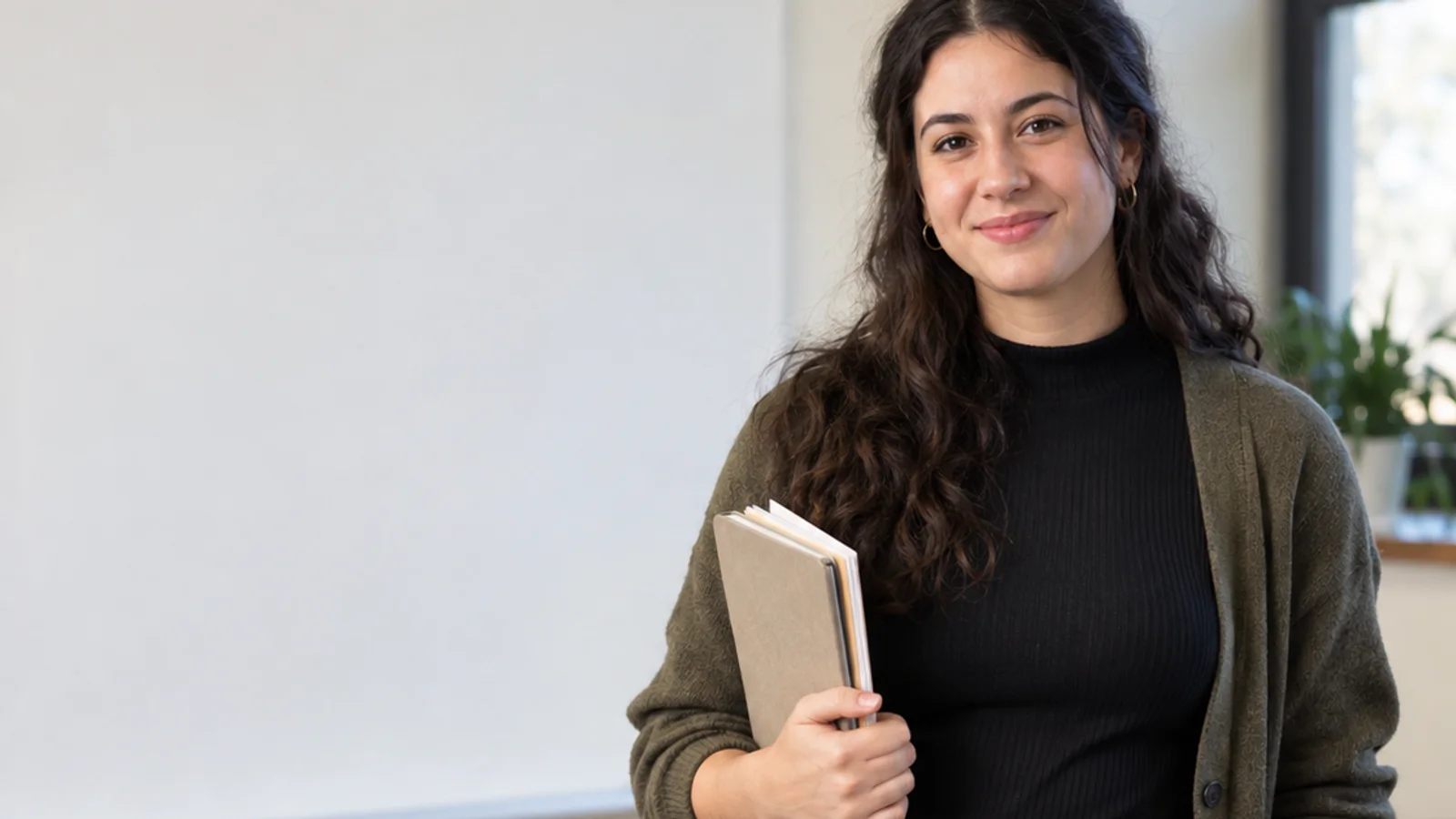 Mid-length portrait of a graduate teaching assistant, education, warm interior light, plain working backdrop with copy space